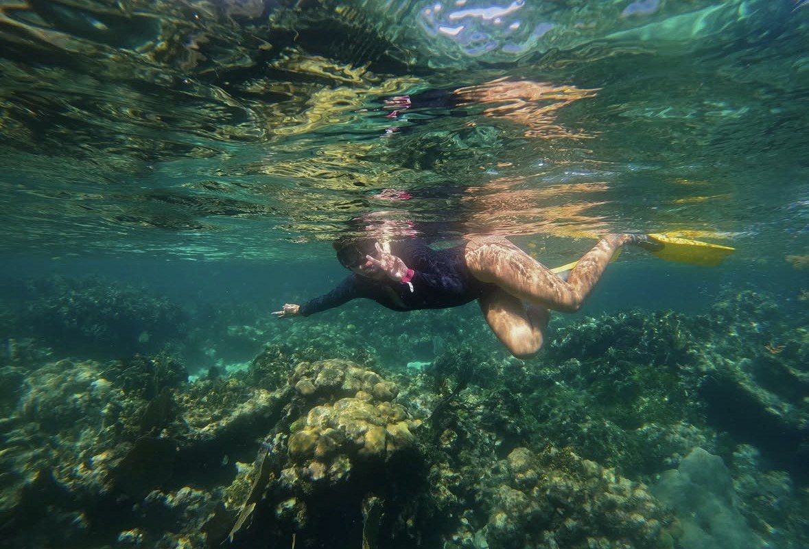Snorkeler in yellow fins drifting just above a rocky Culebra reef