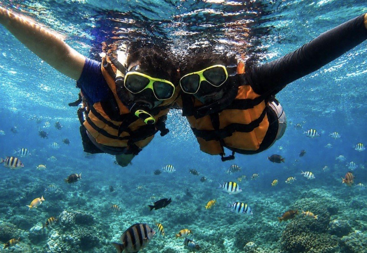 Two friends in life vests side by side above a fish-filled Culebra reef